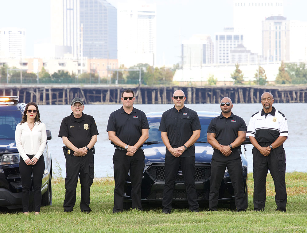 NOLA Protection Group officers with patrol vehicle and the New Orleans skyline